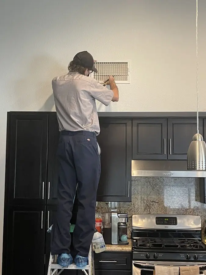 Technician inspecting an air vent during HVAC service in West Richland